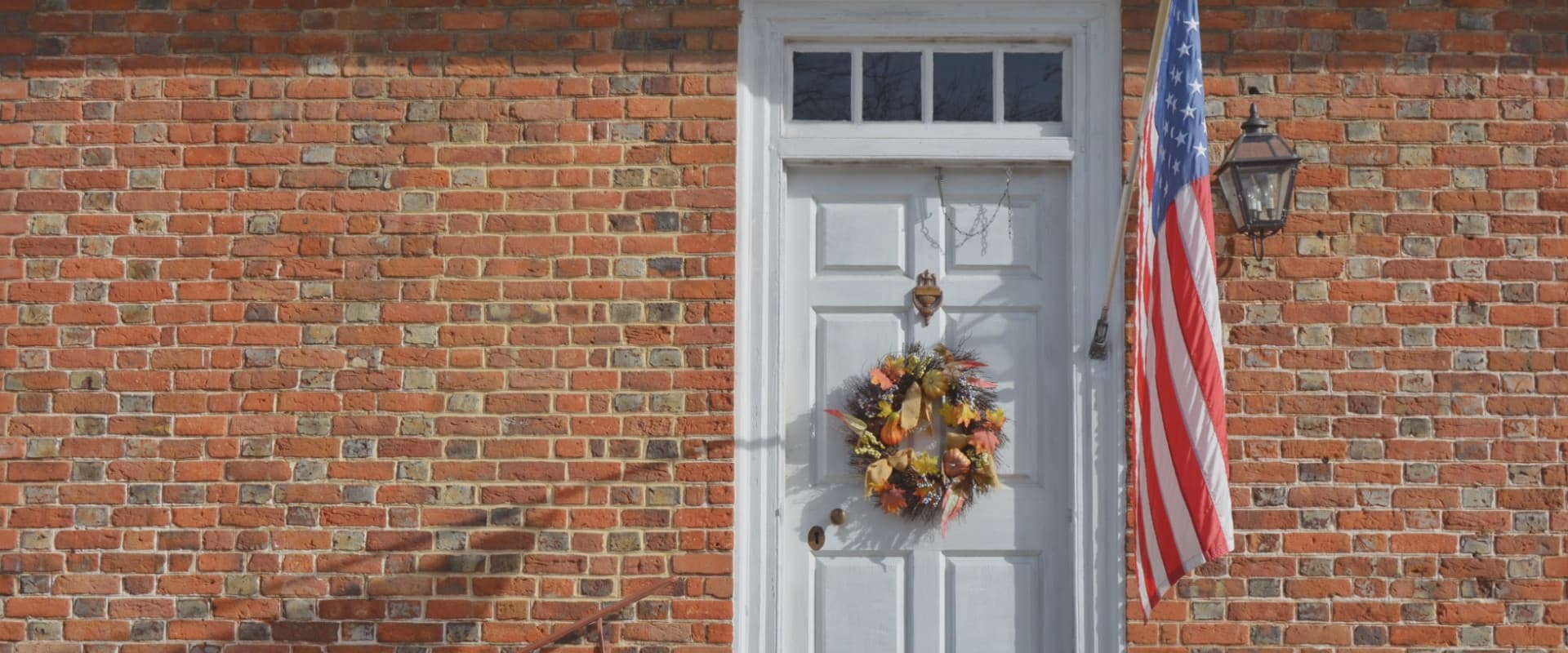 An American flag hanging by a white door.