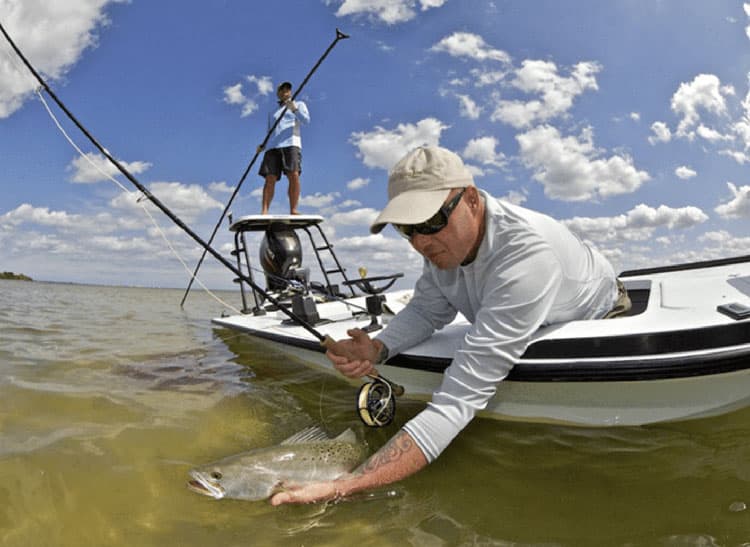 man on a boat catching a fish in the water