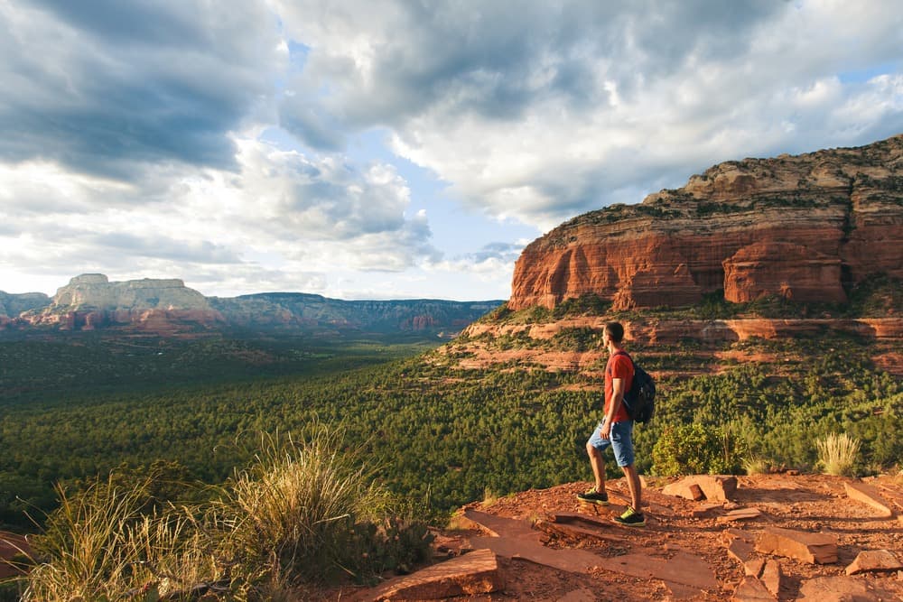 Hiker standing on top of a mountain overlooking a valley and other mountains