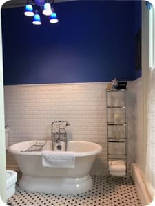A modern bathroom with a clawfoot tub and a shelf for towels