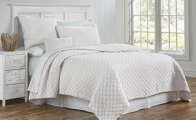 InnStyle coverlet on a made-up bed in a white guest room