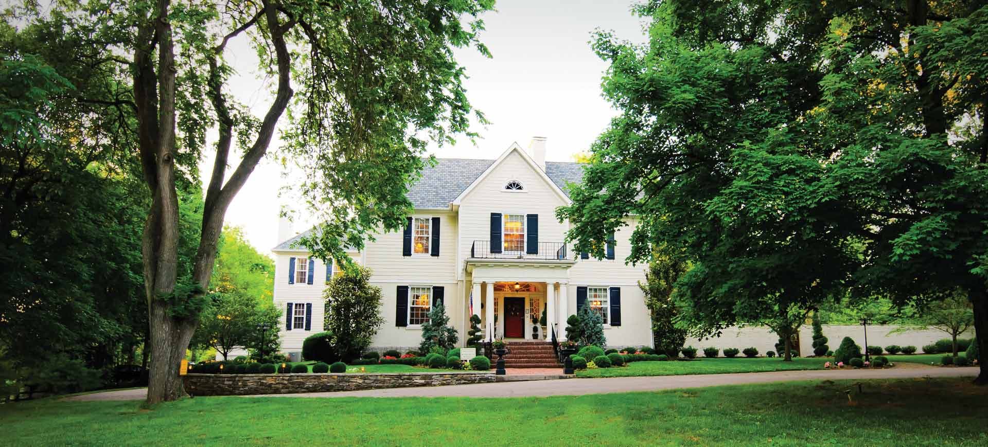 Historic Storybook Inn exterior with green trees and a green lawn out front