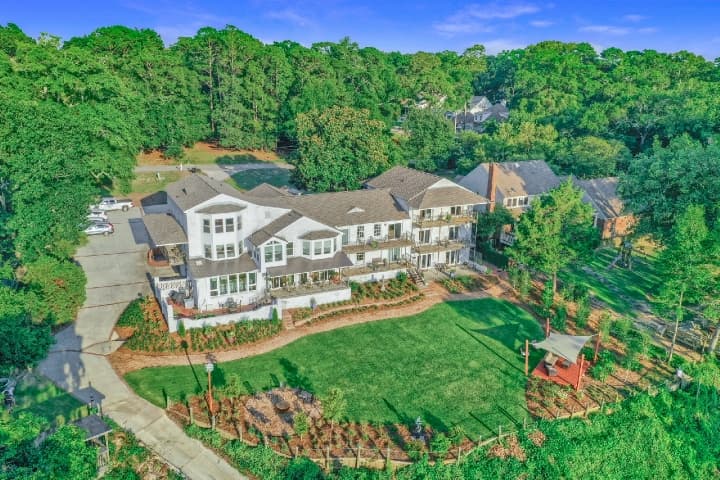 ChatGPT said:  Alt text: Aerial view of Jubilee Suites Boutique B&B in Fairhope, Alabama, surrounded by lush greenery with landscaped grounds overlooking Mobile Bay.