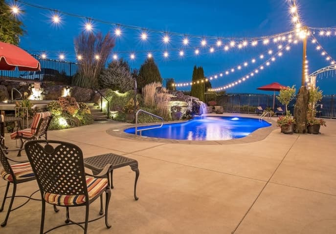 Evening image by the pool with twinkle lights and patio chairs