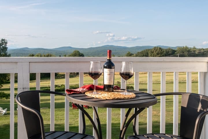Patio table with bottle of red wine and two glasses.
