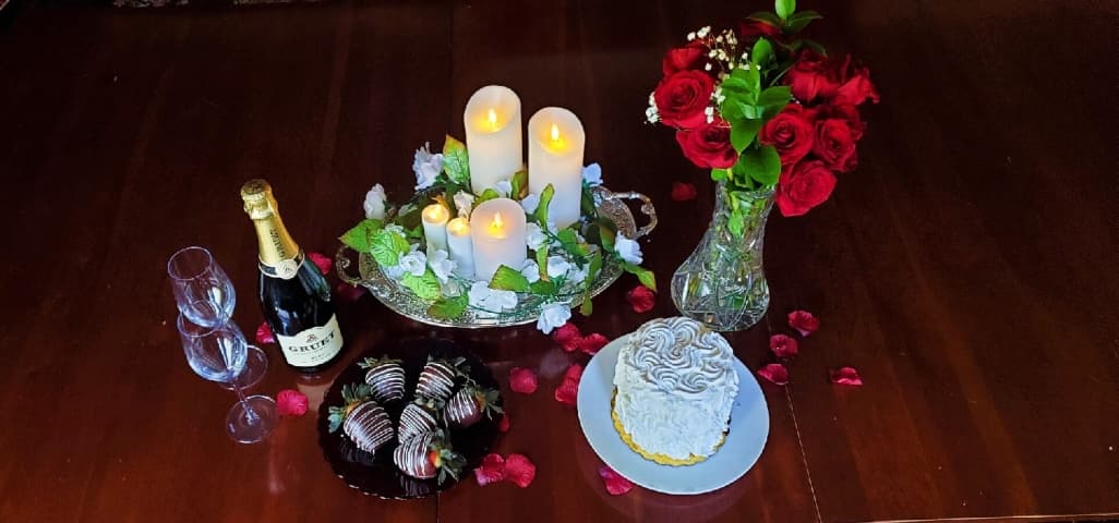 Champagne, chocolate-dipped strawberries, cake, flowers, and candles