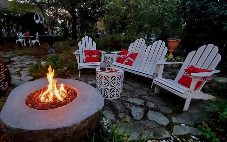 Adirondack chairs surrounding a lit fire table at dusk.