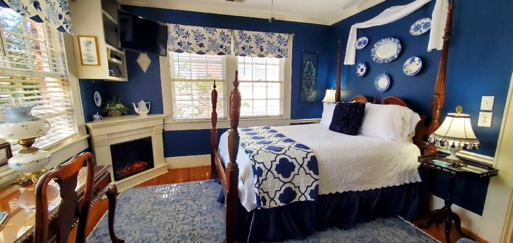 Electric fire place in blue room with white four poster bed.