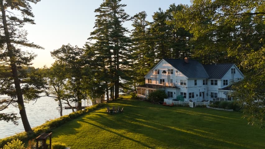 Lawn view of Wolf Cove Inn with trees and lake