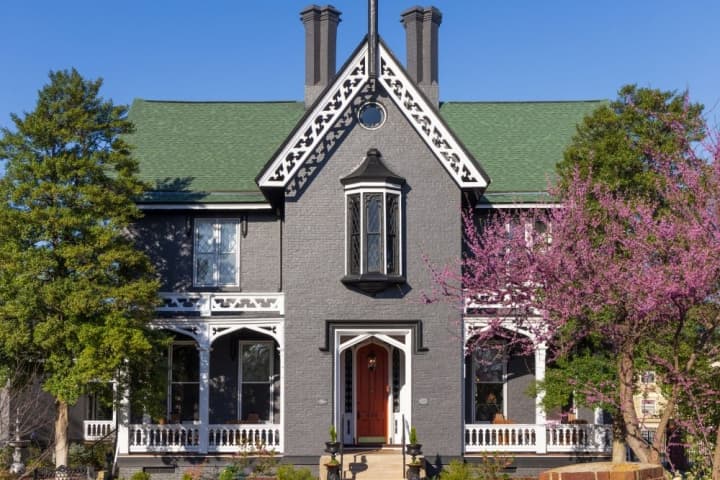 facade of house. gothic and three story painted black with white bargeboard.  Springtime photo with blue sky in background
