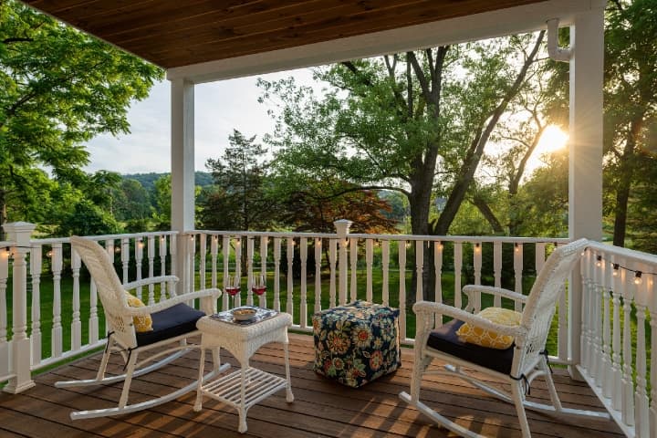 A table with two wine glasses next to rocking chairs on a front porch at a bed and breakfast in Hershey, PA
