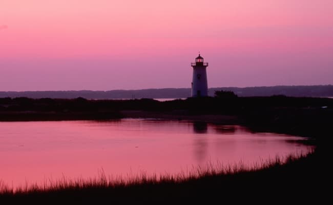A lighthouse by the water at dawn.
