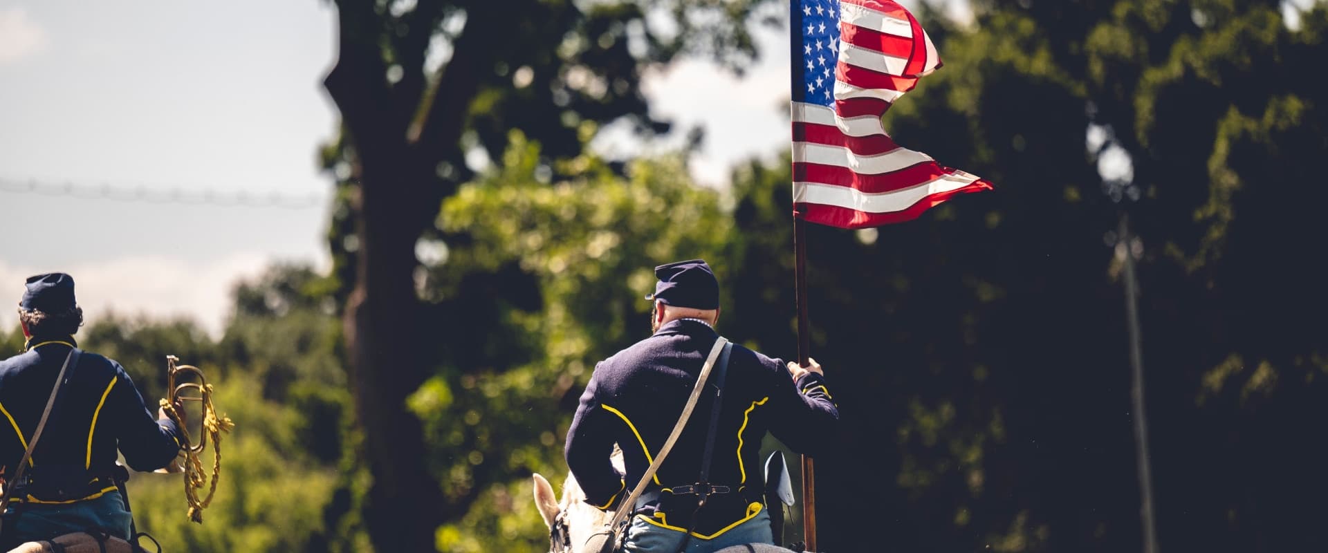 A confederate reenactor riding a horse with a flag