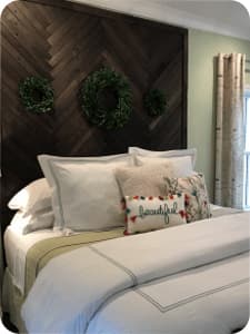 A made up bed with several pillows and blankets