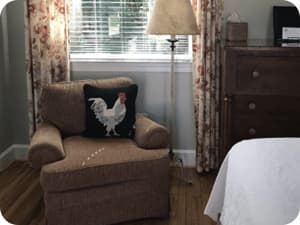 An armchair in the corner of a room next to a window