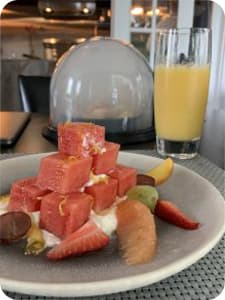Yogurt with fruit stacked on top of it with a glass of orange juice